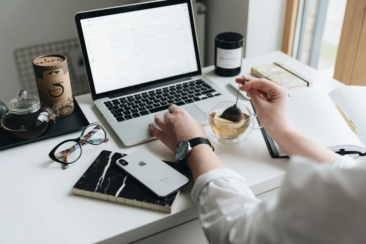 A cozy home office scene with a laptop, tea, and workspace essentials.