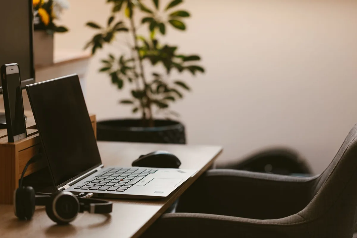 A cozy home office workspace with a laptop, headphones, and a plant. Ideal for remote work.