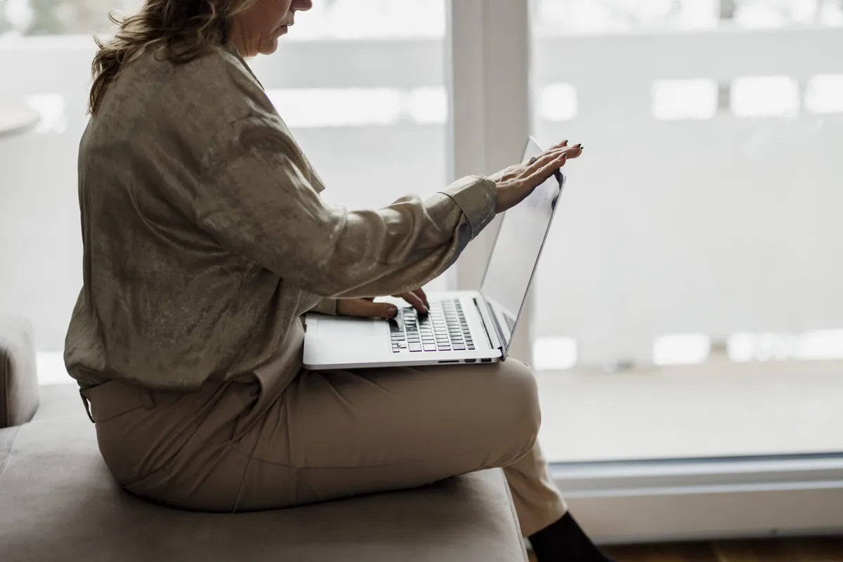 A person working on a laptop near a window